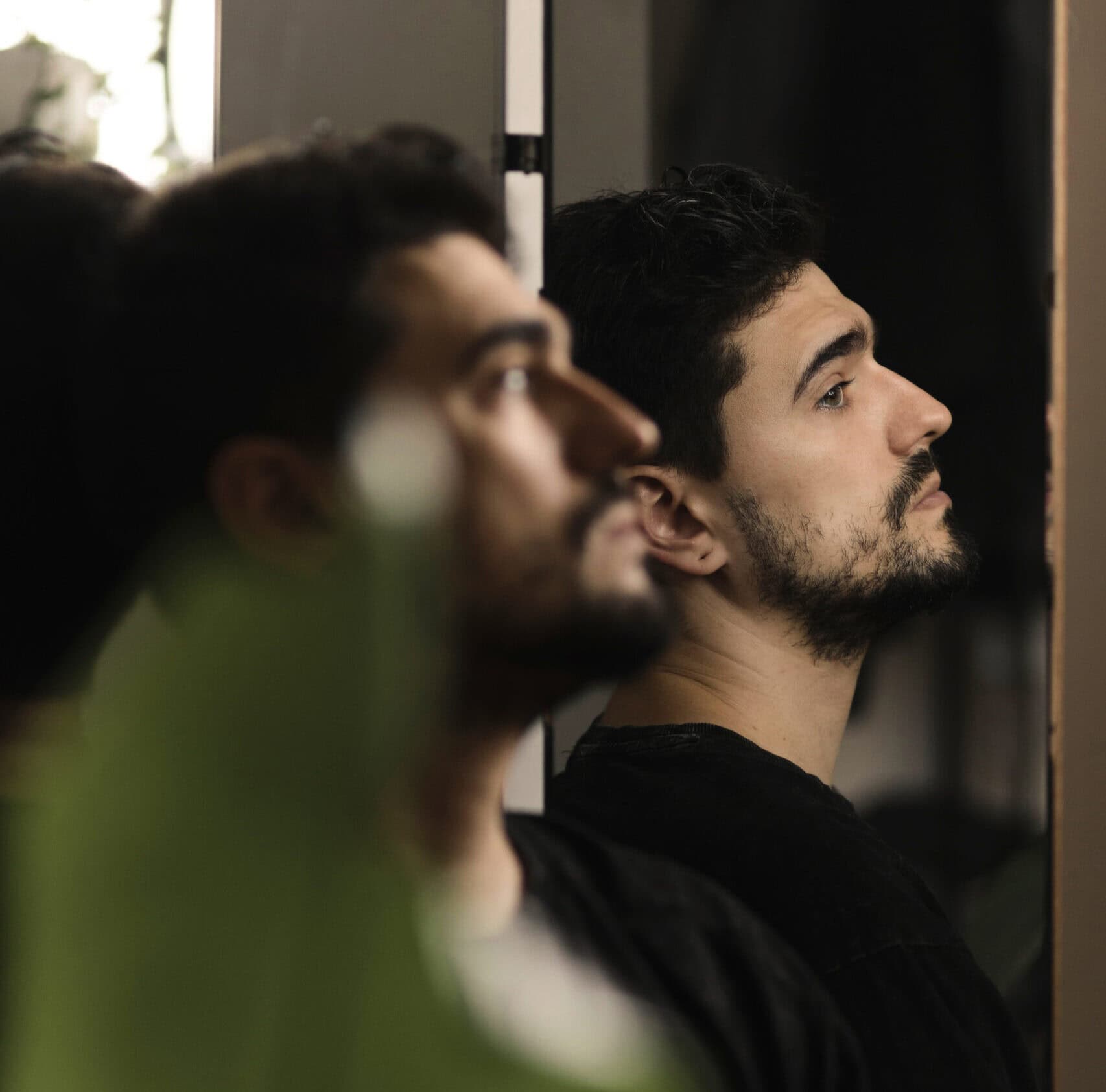 Mann sitzt nachdenklich am Fenster und hadert mich sich selbst